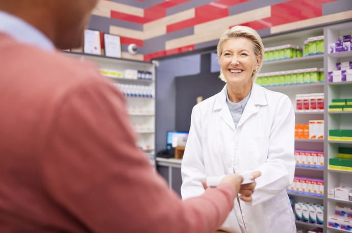 Moringa: czy warto stosować? 5 Starsza pani rozmawia z farmaceutą, bo chce dowiedzieć się, jakie suplementy z moringą warto nabyć.