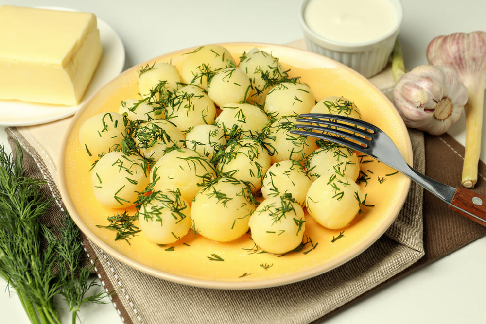 Czy ziemniaki są dobrym wyborem w diecie pudełkowej? Odkryj ich kaloryczność i wpływ na catering dietetyczny 7 Ugotowane ziemniaki z koperkiem, serwowane jako gotowy, zdrowy posiłek, idealny do codziennego jadłospisu.